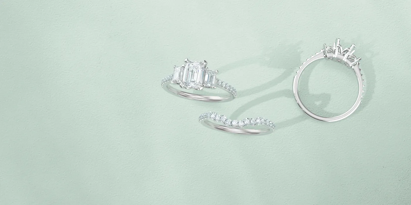 Three elegant silver rings with diamonds on a soft green background. Click to shop designer jewelry at Monarch Jewelry.