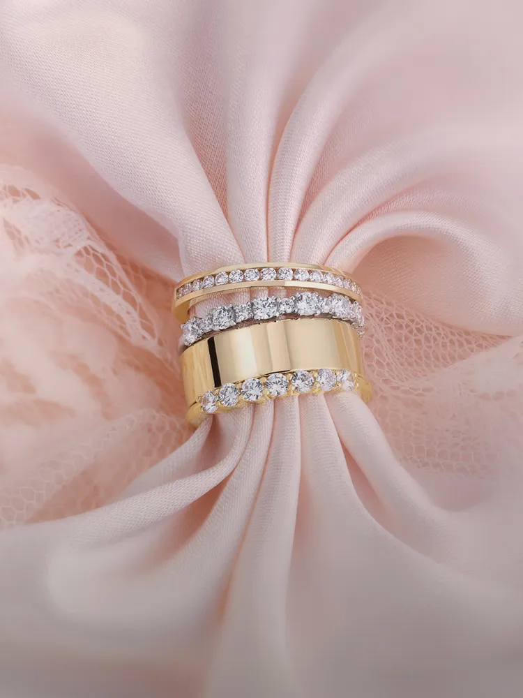 Gold and diamond women's wedding bands displayed on soft pink fabric. Click to shop at Monarch Jewelry in Winter Park.