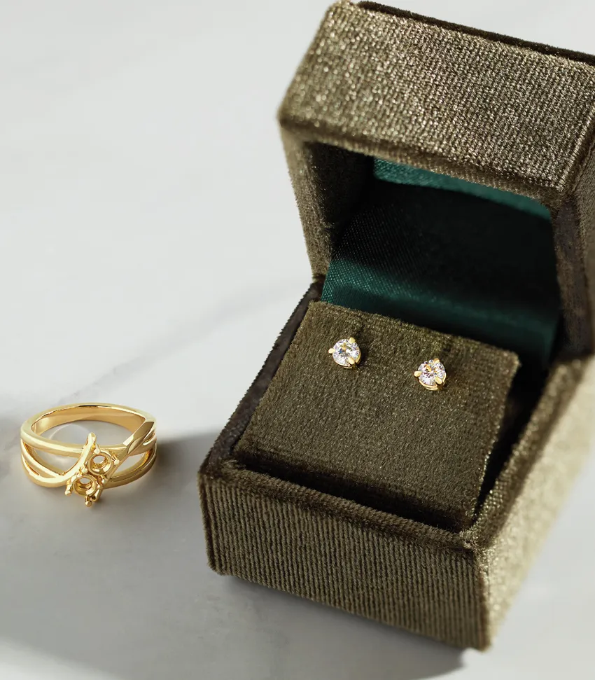 Gold ring and diamond stud earrings displayed in a velvet jewelry box. Visit Monarch Jewelry in Winter Park for more.