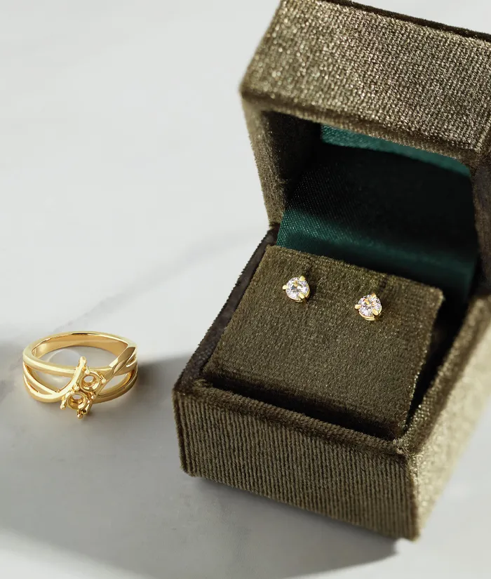 Gold ring and diamond stud earrings displayed in a velvet jewelry box. Visit Monarch Jewelry in Winter Park for more.