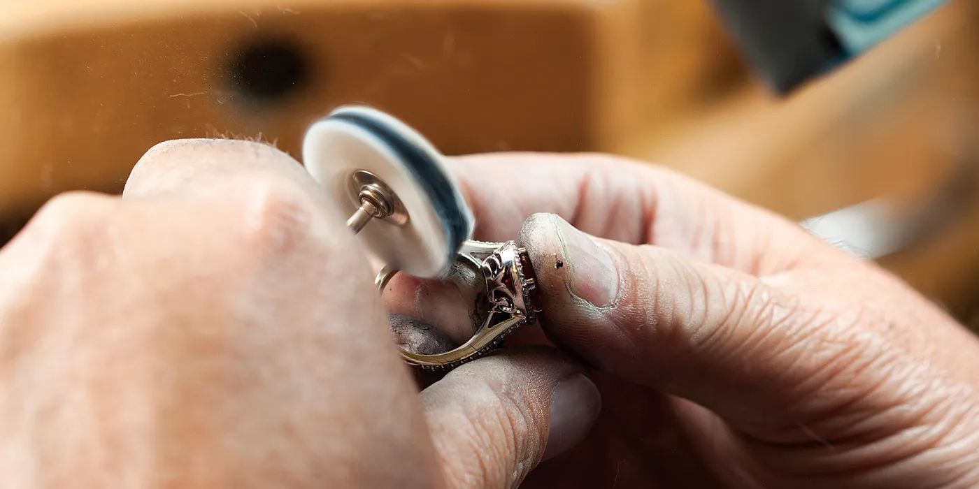Jeweler polishing a ring with a tool, showcasing craftsmanship at Monarch Jewelry in Winter Park.