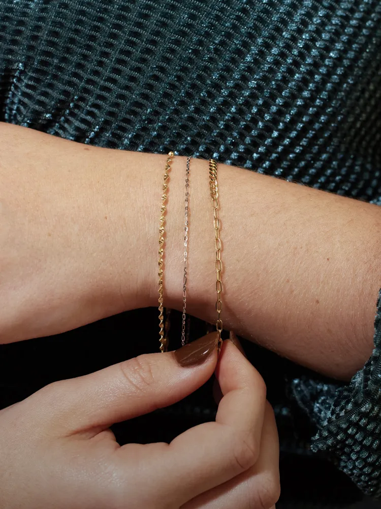 Three delicate bracelets in gold and rose gold worn on a wrist, showcasing fine jewelry from Monarch Jewelry. Shop now!