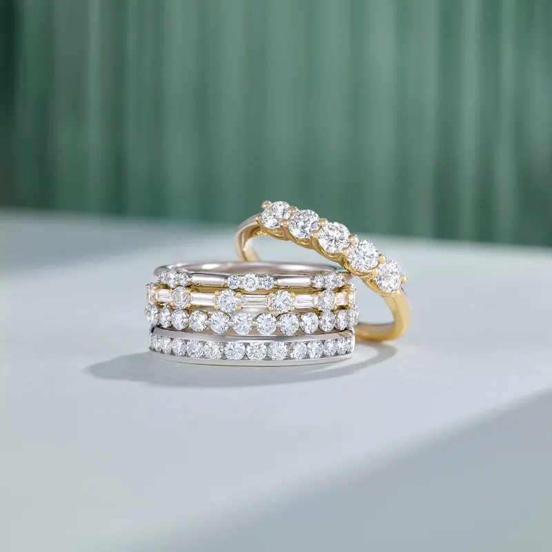 Three elegant diamond rings in white and yellow gold, showcasing sparkling stones, displayed on a light surface.