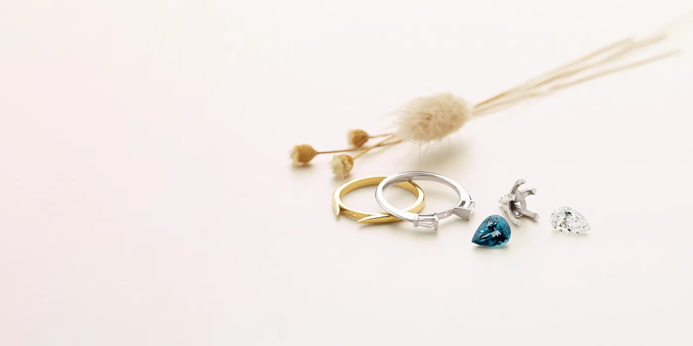 Custom jewelry pieces including rings and gemstones on a soft background.