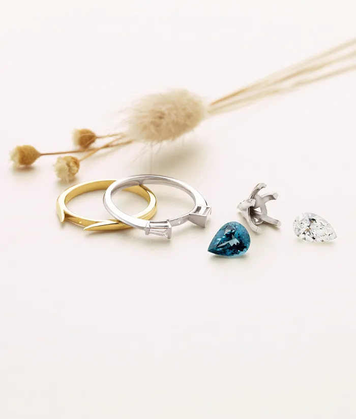 Custom jewelry pieces including rings and gemstones on a soft background.