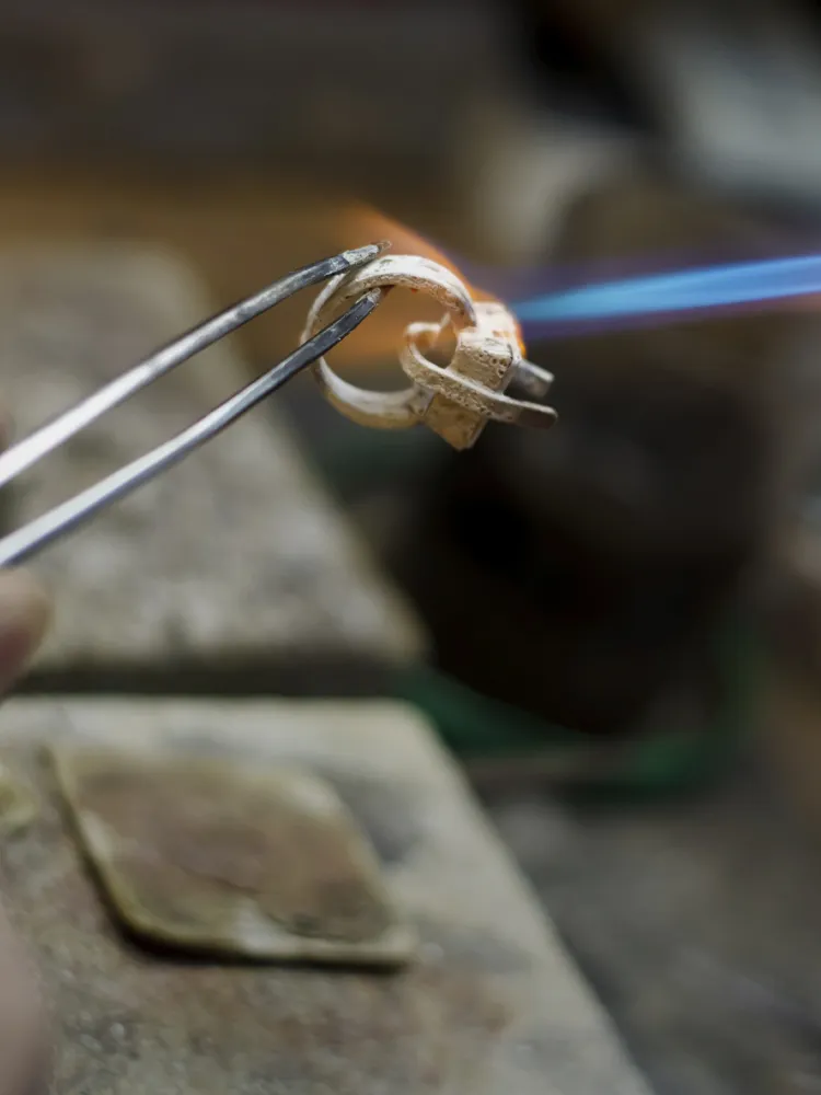 A jeweler uses tweezers to hold a ring while applying a flame for redesigning at Monarch Jewelry in Winter Park.