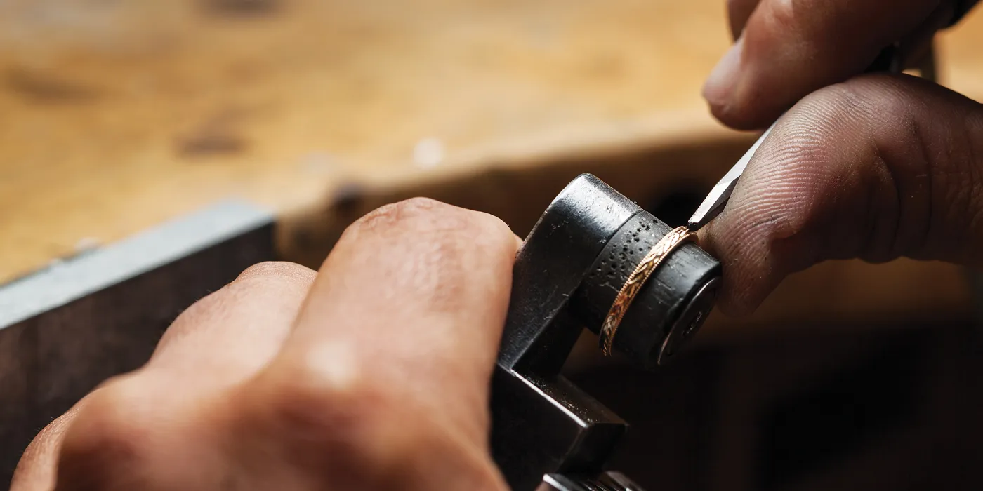 A jeweler meticulously crafting a gold ring using specialized tools at Monarch Jewelry in Winter Park.