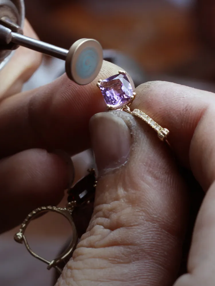 Jeweler polishing a purple gemstone ring, showcasing intricate craftsmanship at Monarch Jewelry in Winter Park.