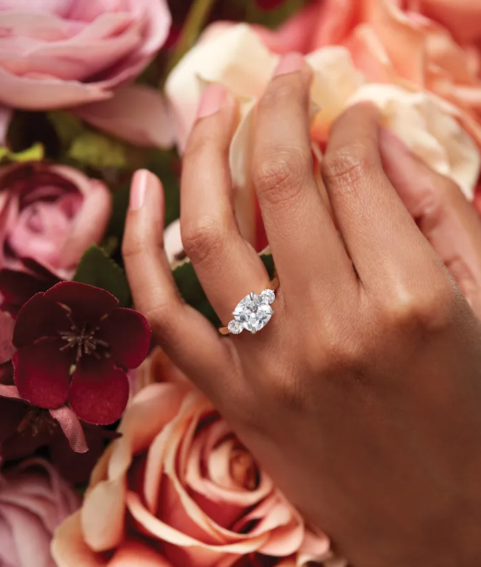 A bride holding a bouquet of white roses and orchids, adorned with elegant jewelry. Visit Monarch Jewelry for more.