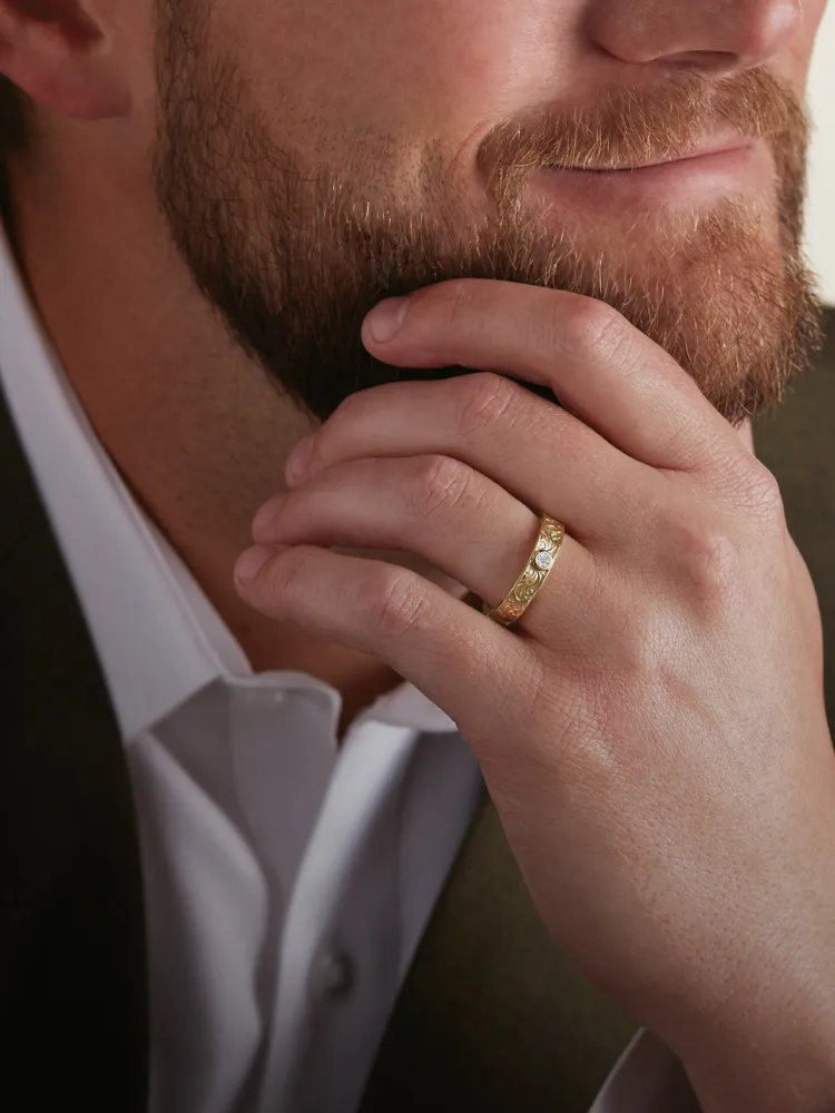 Man wearing a gold ring, resting his chin on his hand, promoting men's bands at Monarch Jewelry, Winter Park. Shop now!