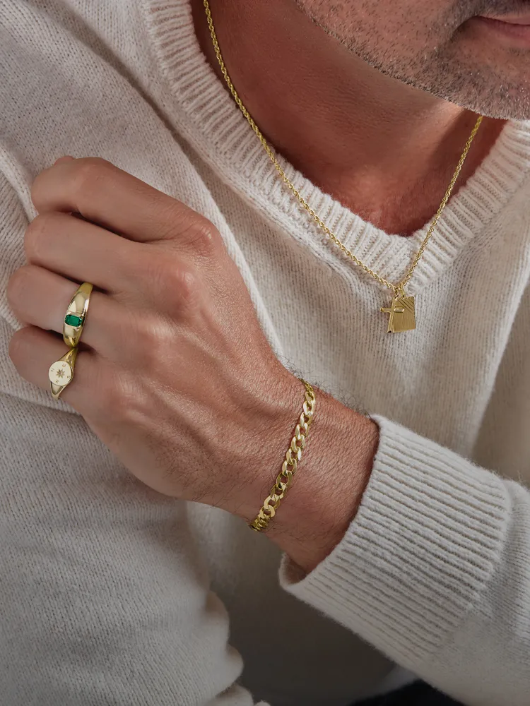 Stylish men's jewelry featuring gold chain, ring with green stone, and pendant necklace. Shop at Monarch Jewelry, Winter Park.