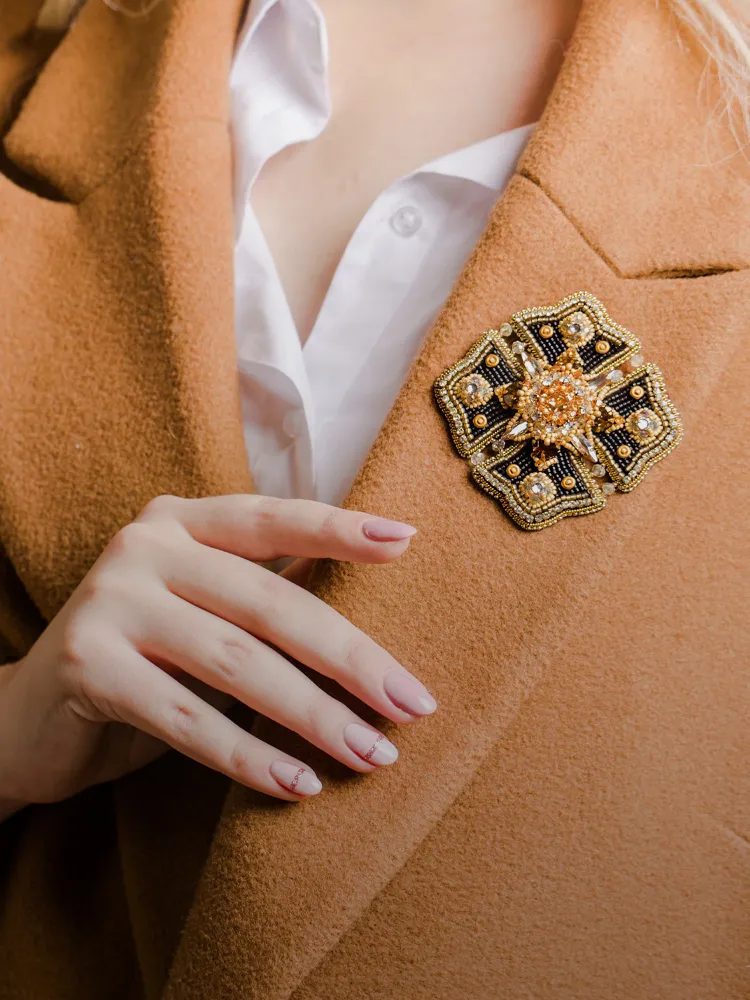 Elegant brooch on a coat, featuring intricate beadwork and a floral design. Shop Pins & Brooches at Monarch Jewelry.