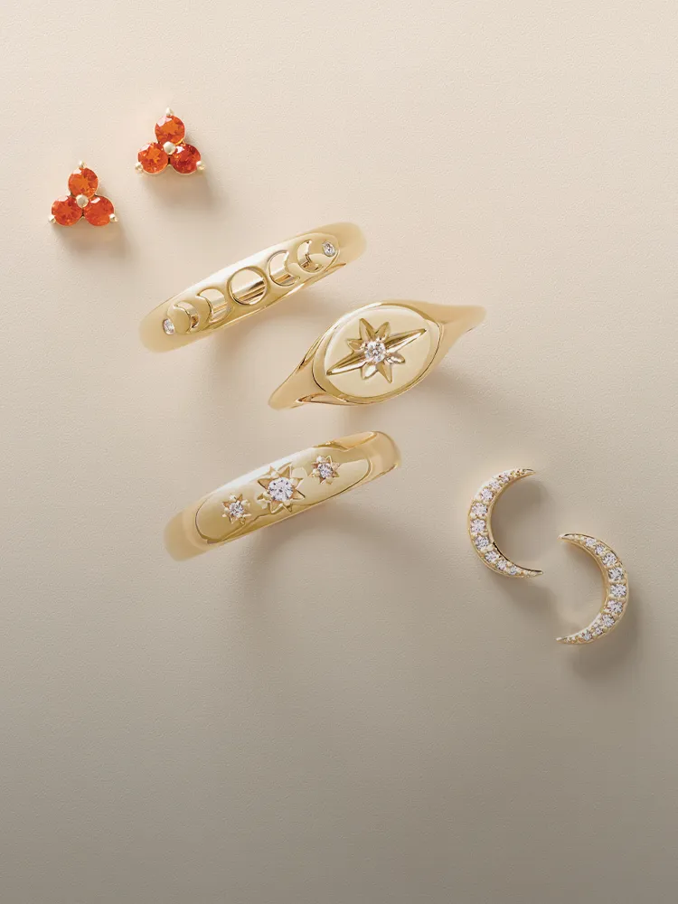 Gold rings and earrings with gemstones displayed on a neutral background. Shop Fashion Rings at Monarch Jewelry, Winter Park.