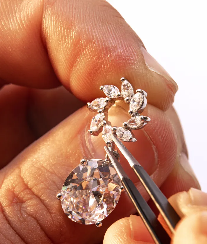 A jeweler delicately holds a diamond earring with tweezers, showcasing intricate details and craftsmanship.
