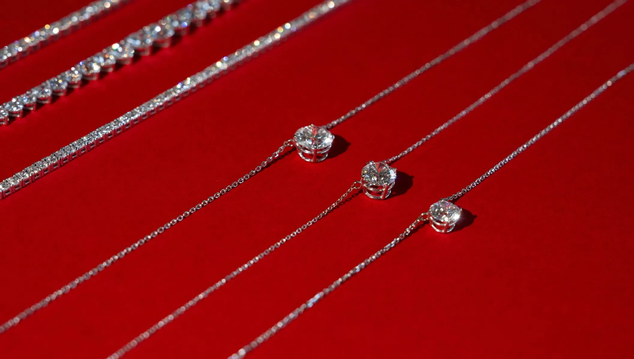 Diamond pendants from Laredo's Moore Jewelers on a red background