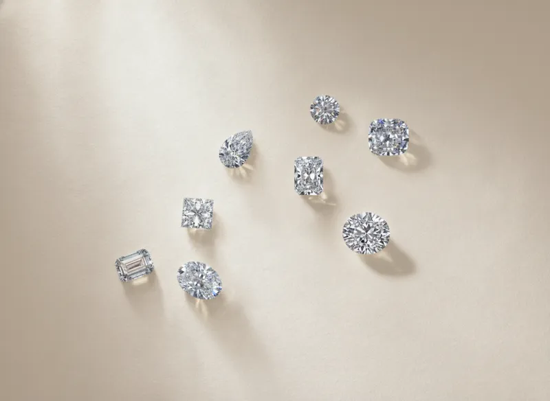Loose diamonds in several shapes on a cream surface