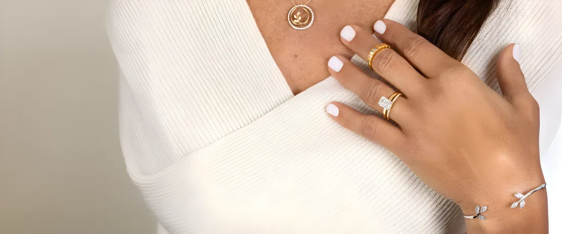 A woman wearing a diamond ring, gold rings and a gold medallion necklace
