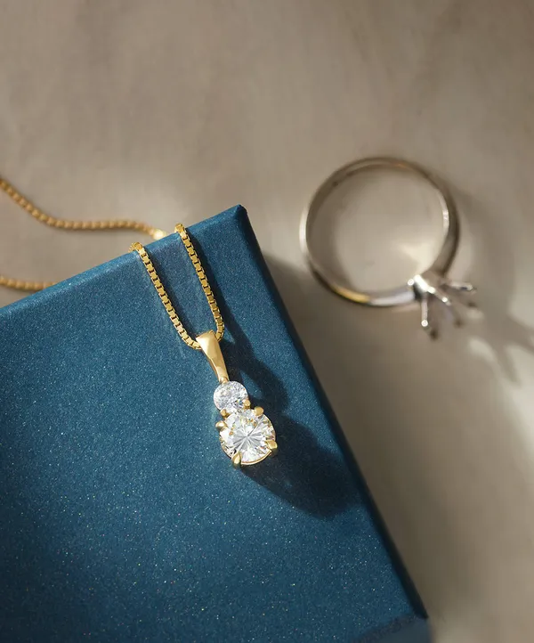 A diamond pendant and diamond ring on a navy jewelry box