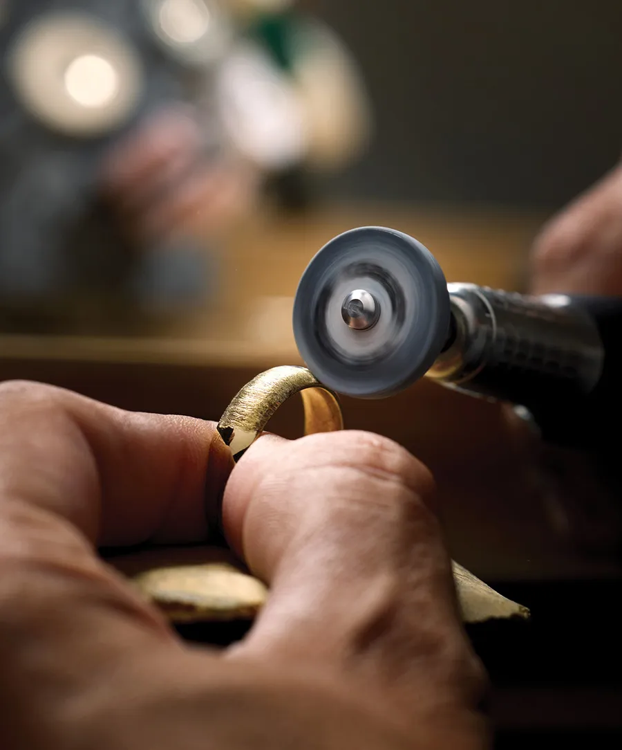 A bench jeweler polishing a gold ring at the Morin Jewelers workbench