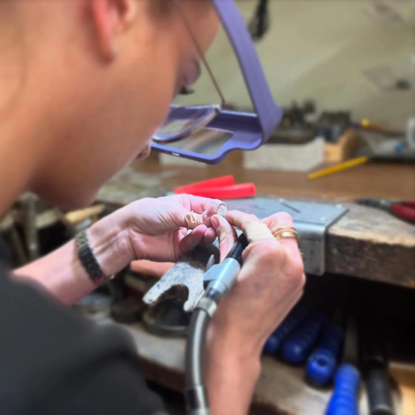 A man in a suit shows off a green watch while another person adjusts it on his wrist.
