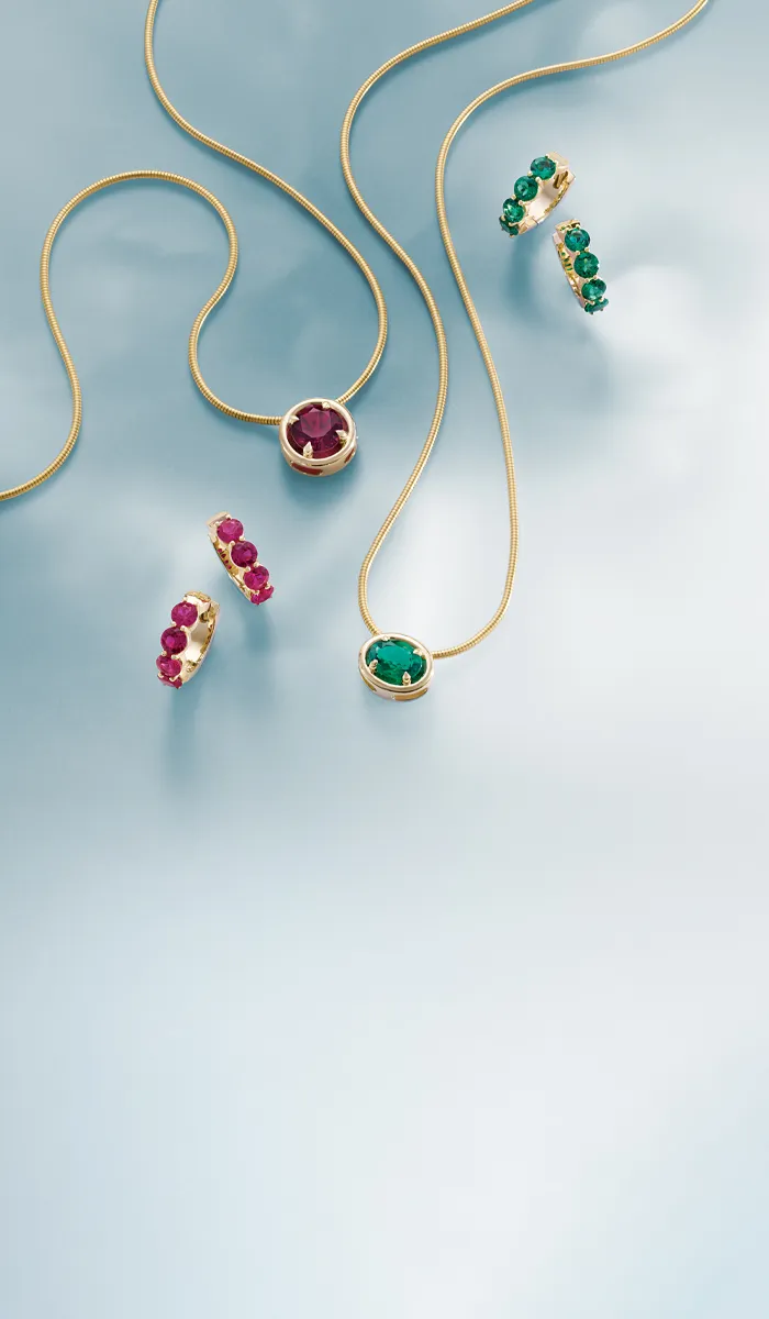 Elegant gold jewelry featuring a ruby pendant necklace and emerald earrings. Click to shop now at Nelson Jewelry, Ltd.