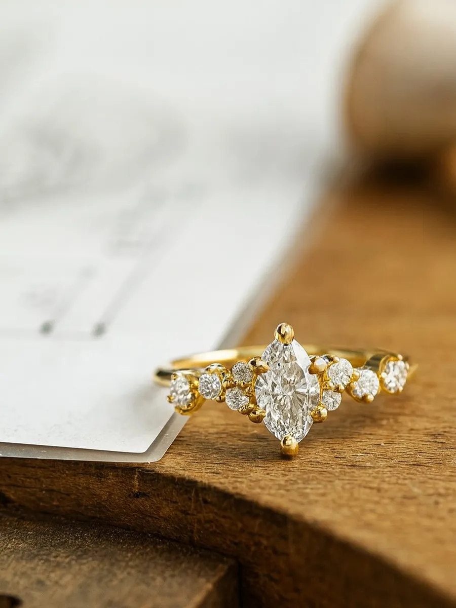 Elegant gold ring with a marquise diamond center and smaller diamonds on the band, displayed on a wooden surface.