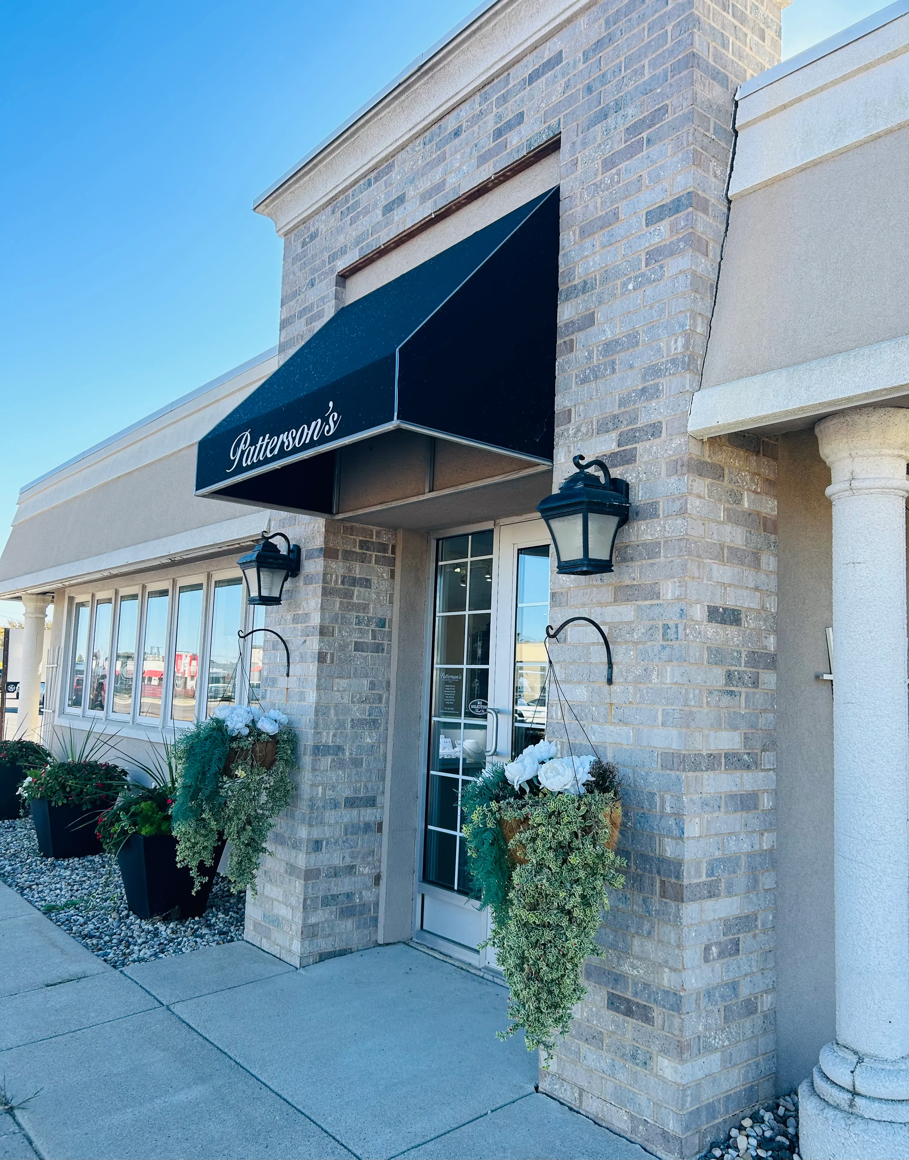 Patterson's Diamond Center storefront with black awning, floral arrangements, and welcoming entrance in Mankato.