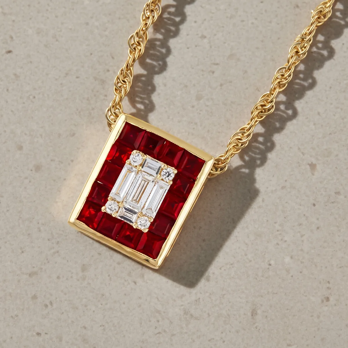 Gold necklace with a rectangular pendant featuring red and white gemstones.