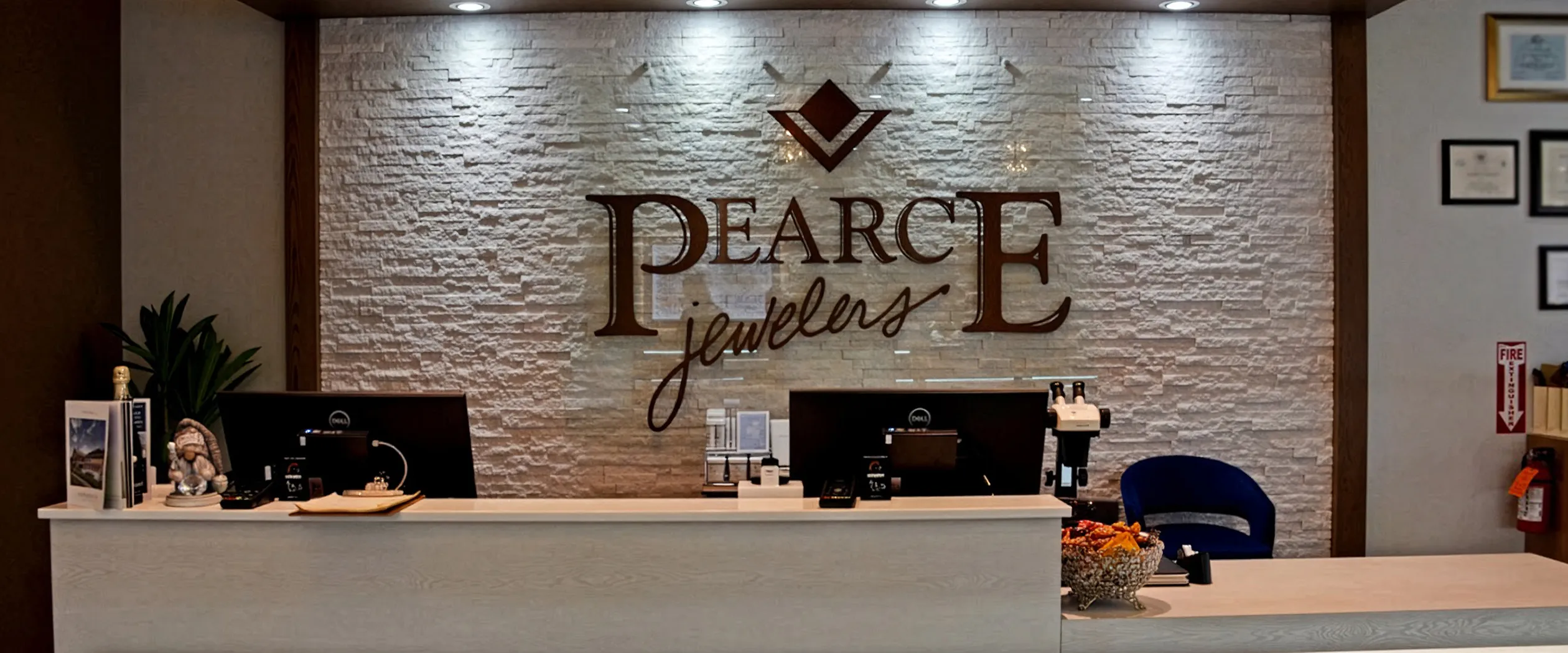 Reception desk at Pearce Jewelers with logo on stone wall, West Lebanon, NH.