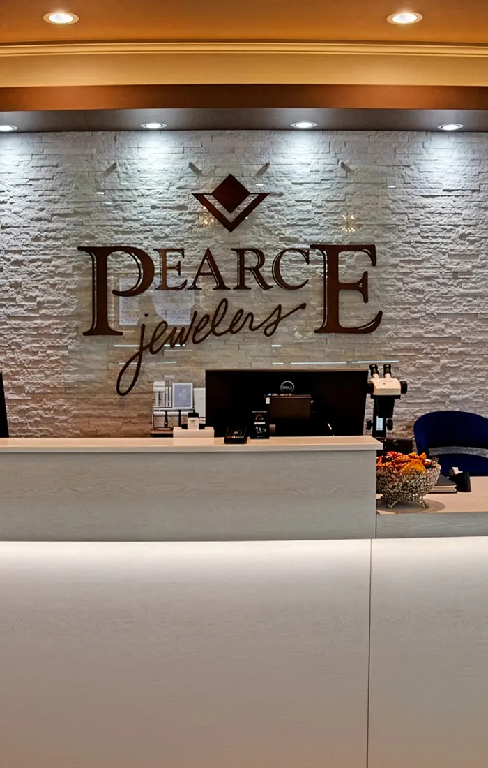 Reception desk at Pearce Jewelers with logo on stone wall, West Lebanon, NH.