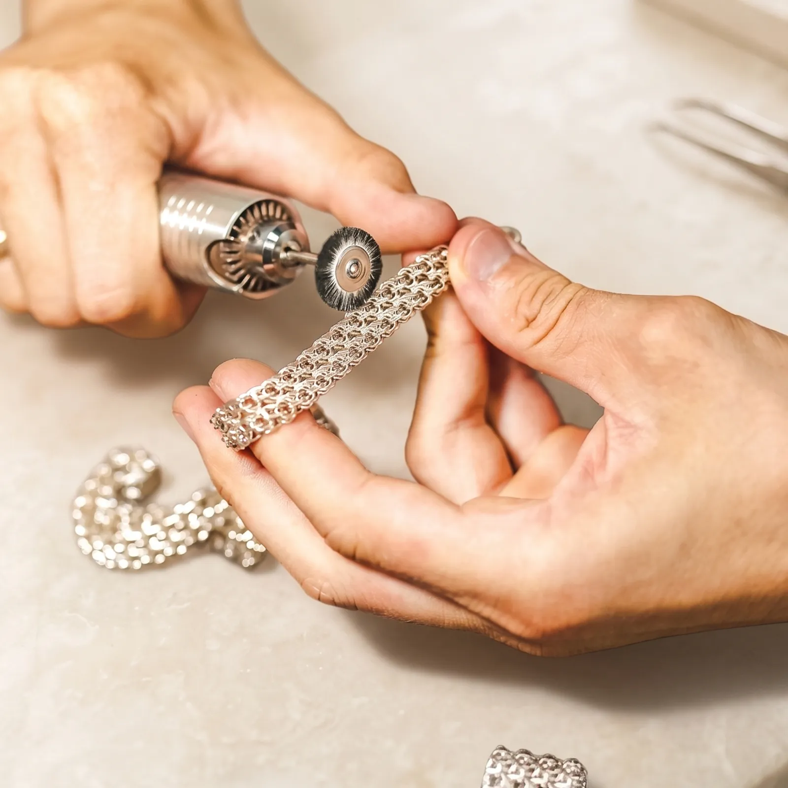 Jeweler polishing a silver bracelet with a rotary tool. Learn more about jewelry services at Pearce Jewelers.