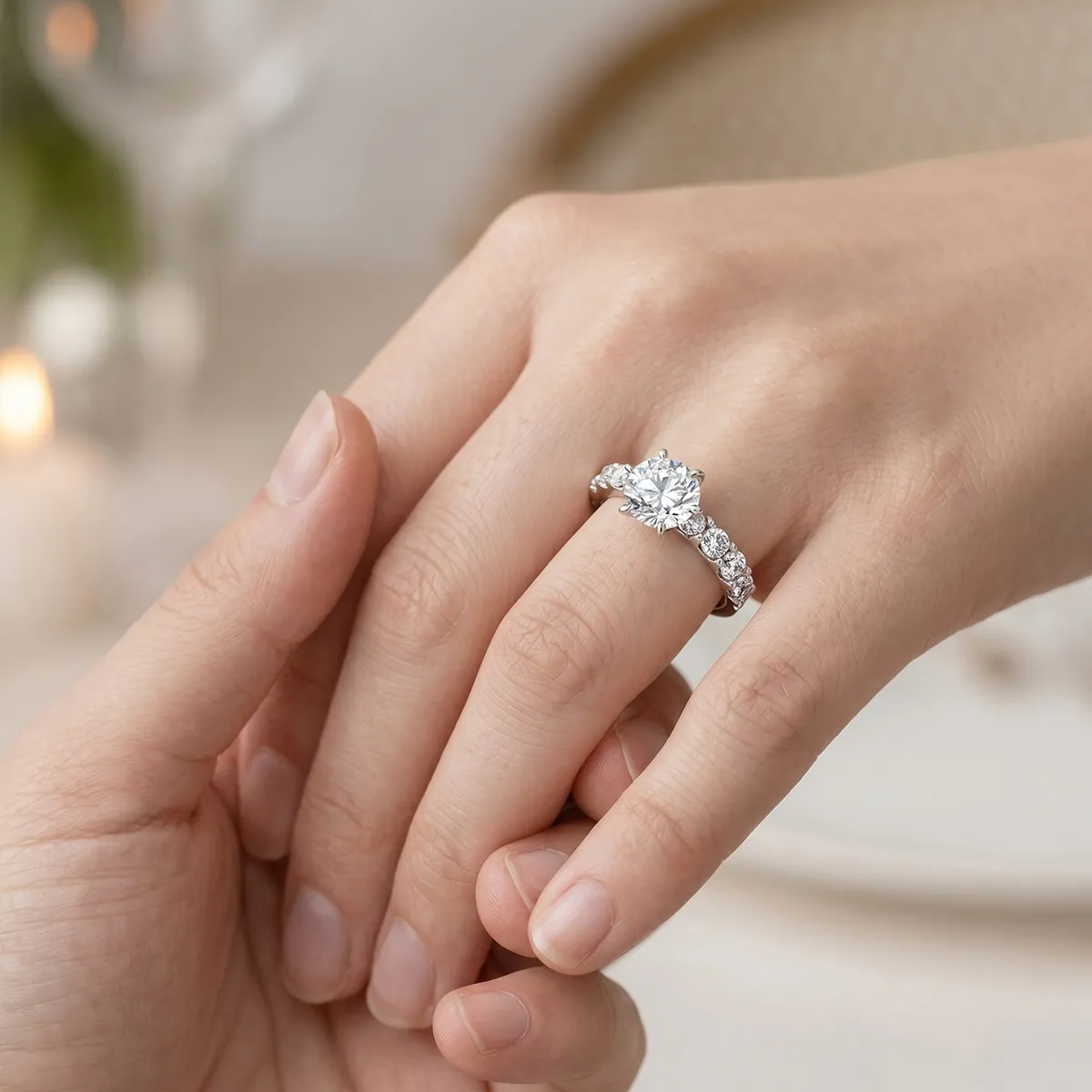A hand with a diamond engagement ring being held gently, showcasing the jewelry.