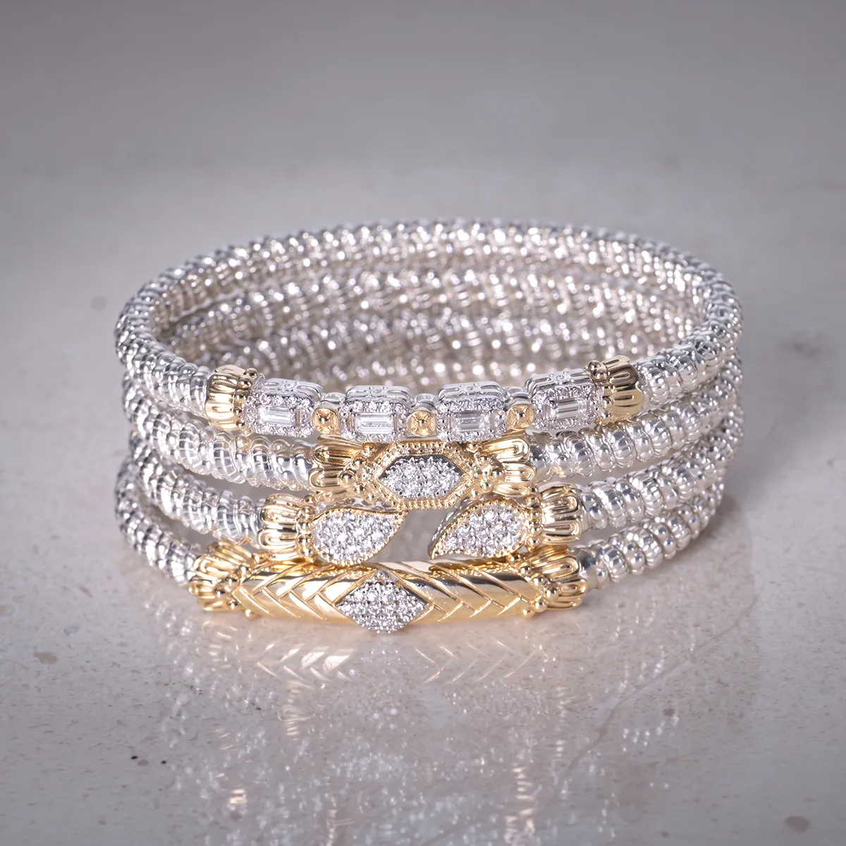 Elegant silver and gold bracelet with intricate design displayed on a reflective surface.