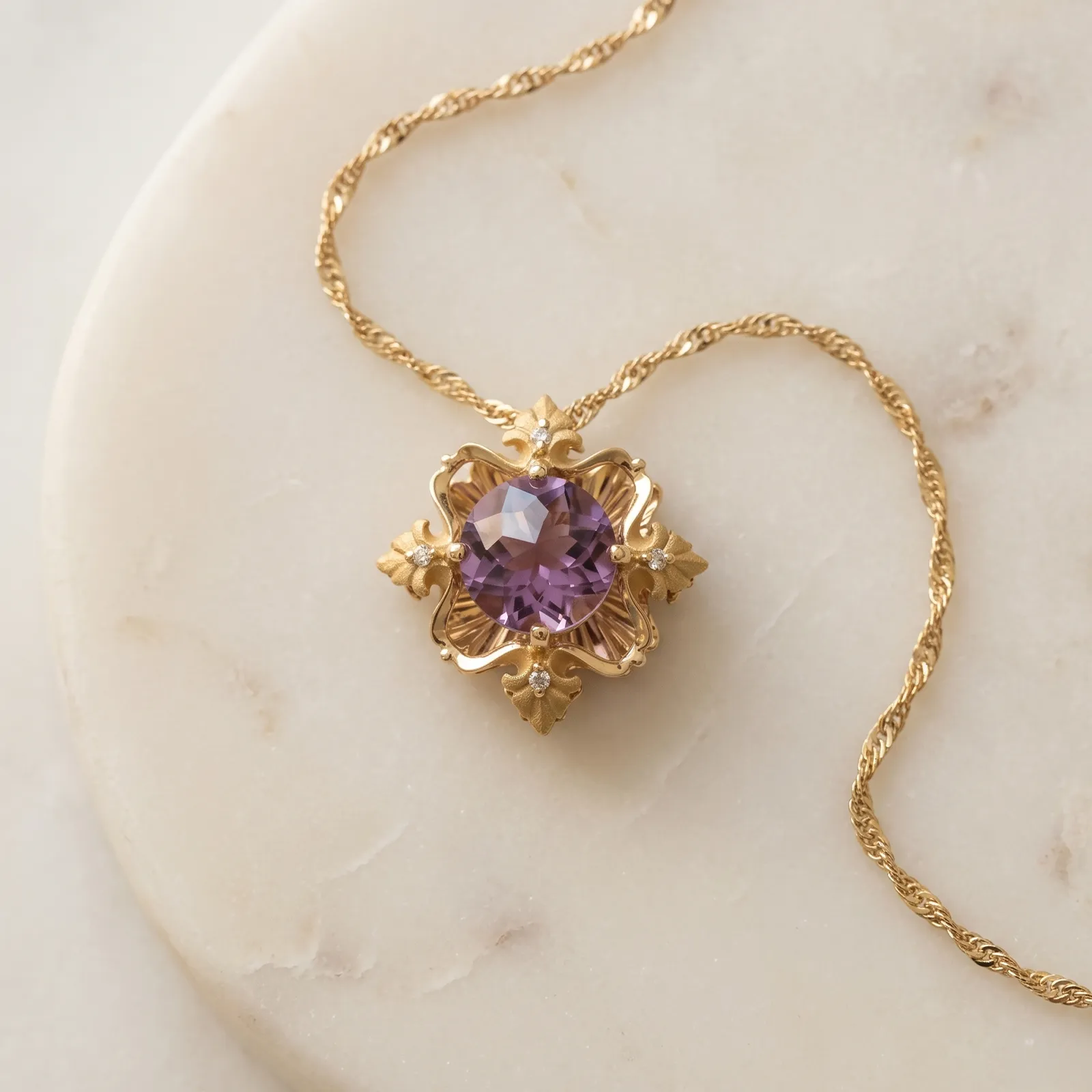 Elegant gold necklace with a purple gemstone pendant on a marble surface.