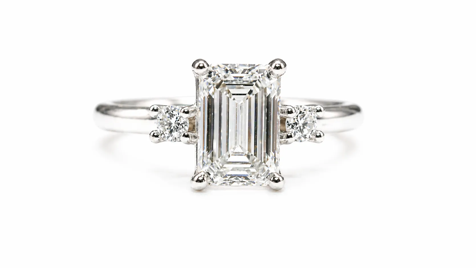 Emerald-cut diamond ring with two round side stones on a white background.