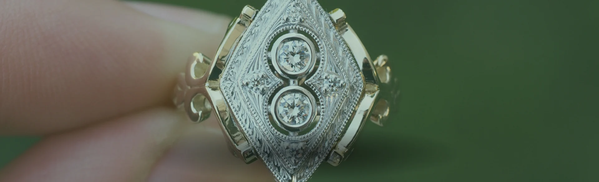 A hand holding an engraved antique diamond ring