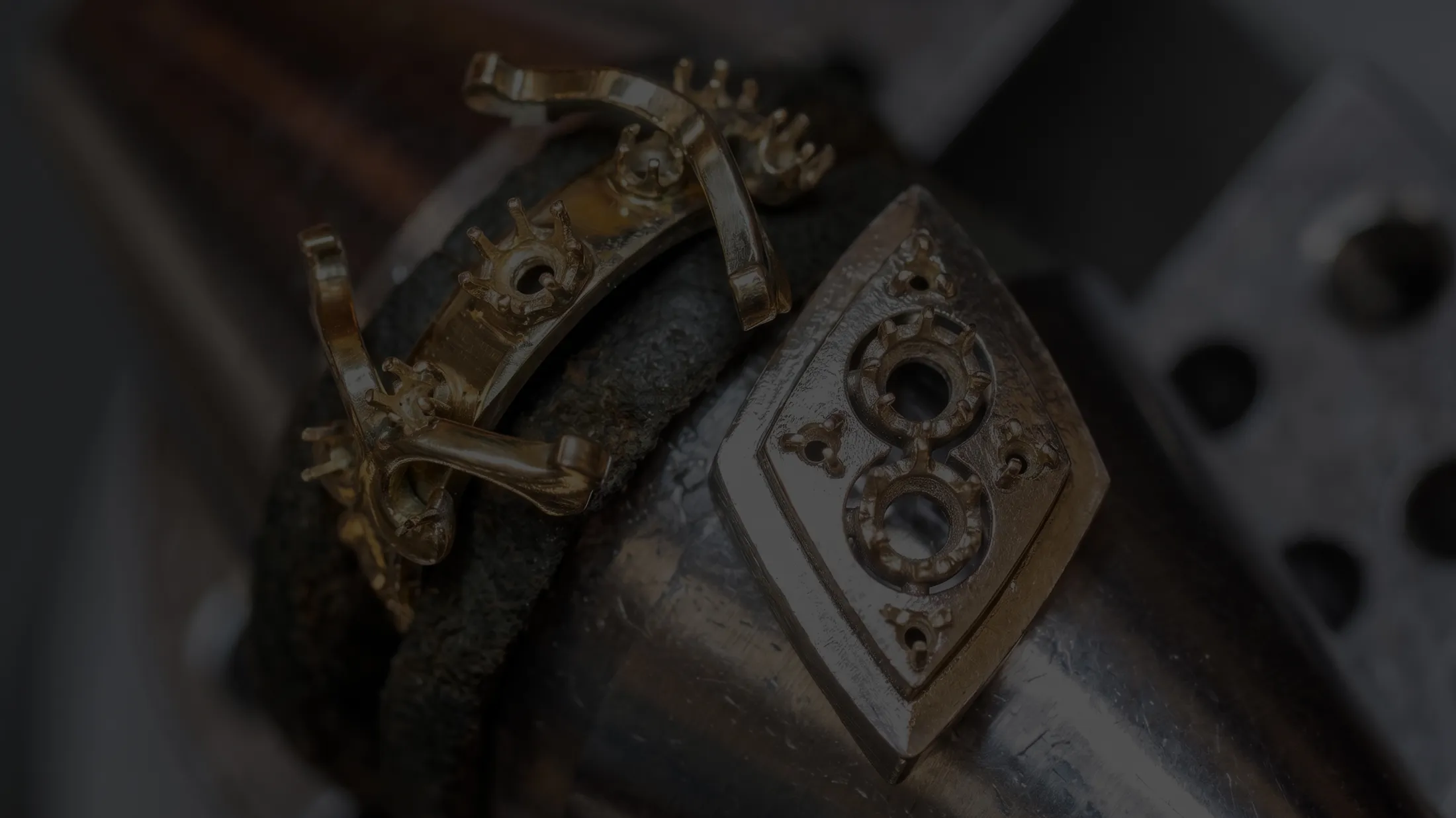 Close-up of intricate gold and silver jewelry settings on a metal tool.