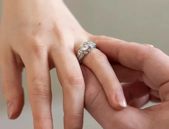 A diamond ring being placed on a person's finger.
