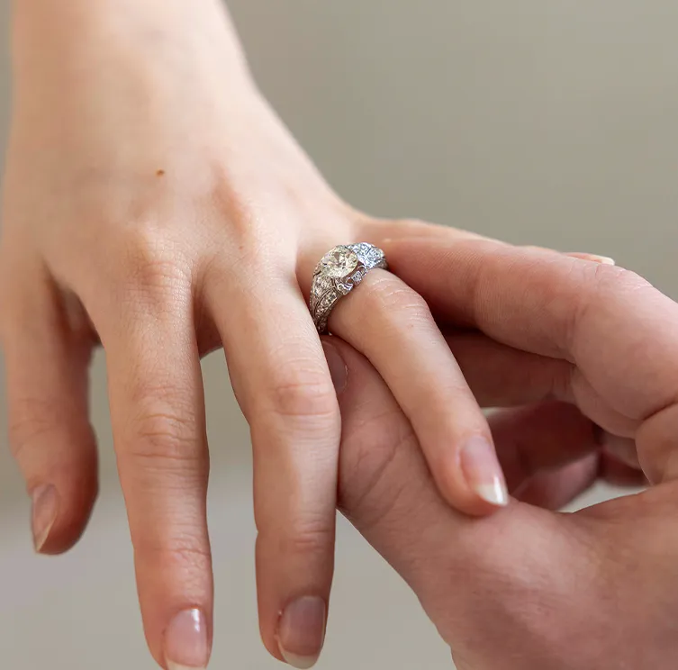 A diamond ring being placed on a person's finger.