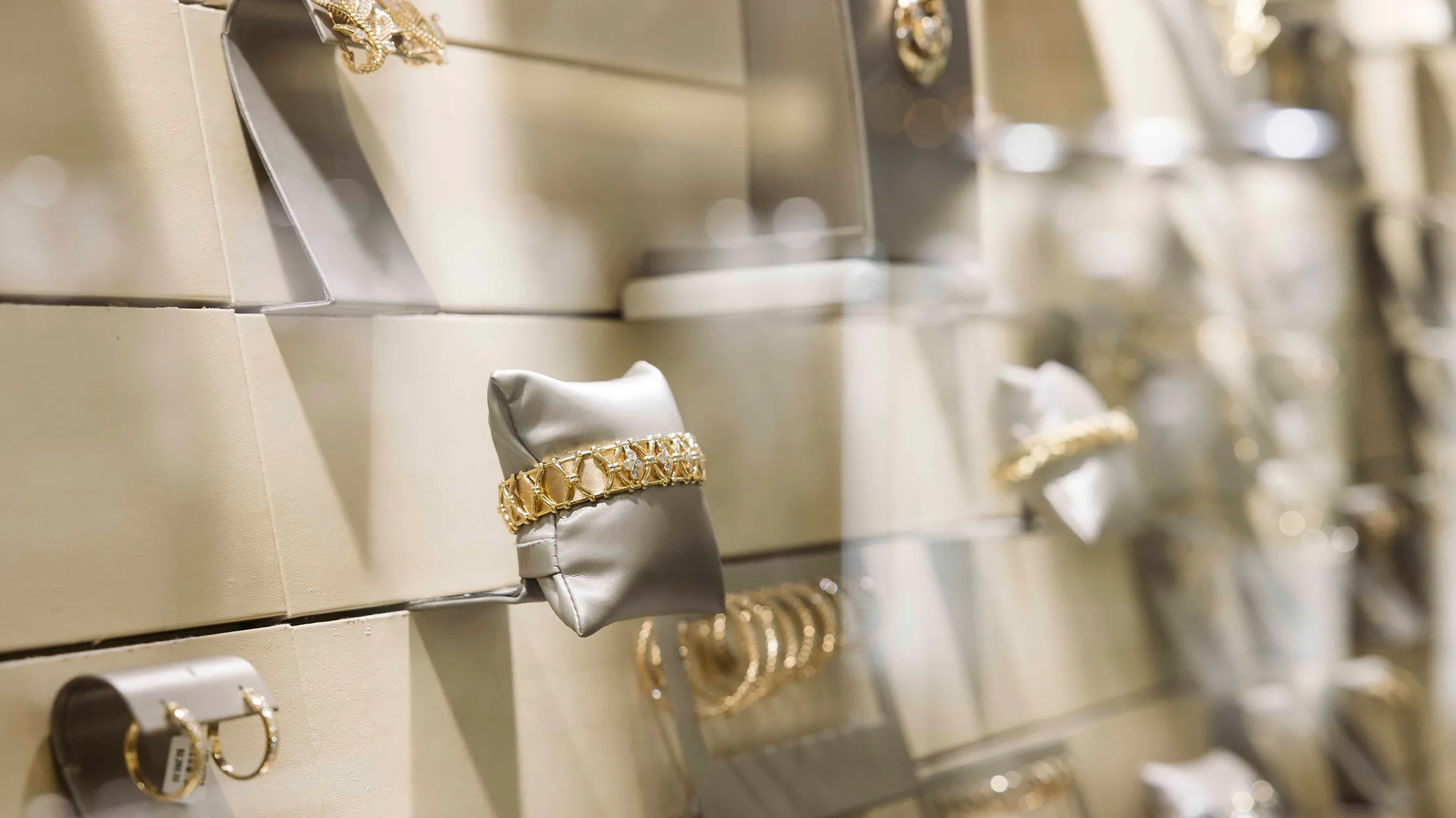 Jewelry display with gold bracelets and earrings on stands in a showroom.