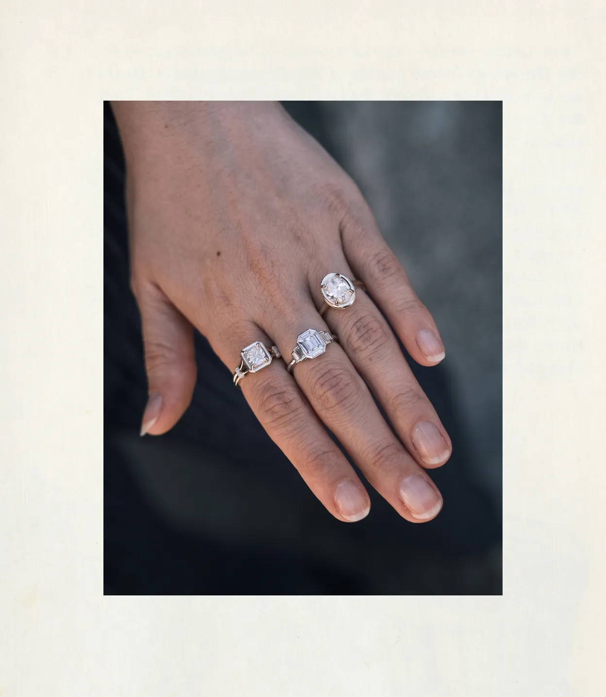 Hand wearing three rings with large gemstones on different fingers.