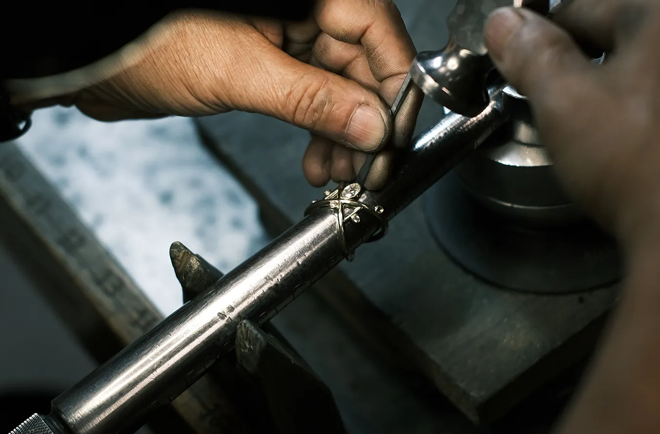 A jeweler checking a diamond ring against a ring mandrel