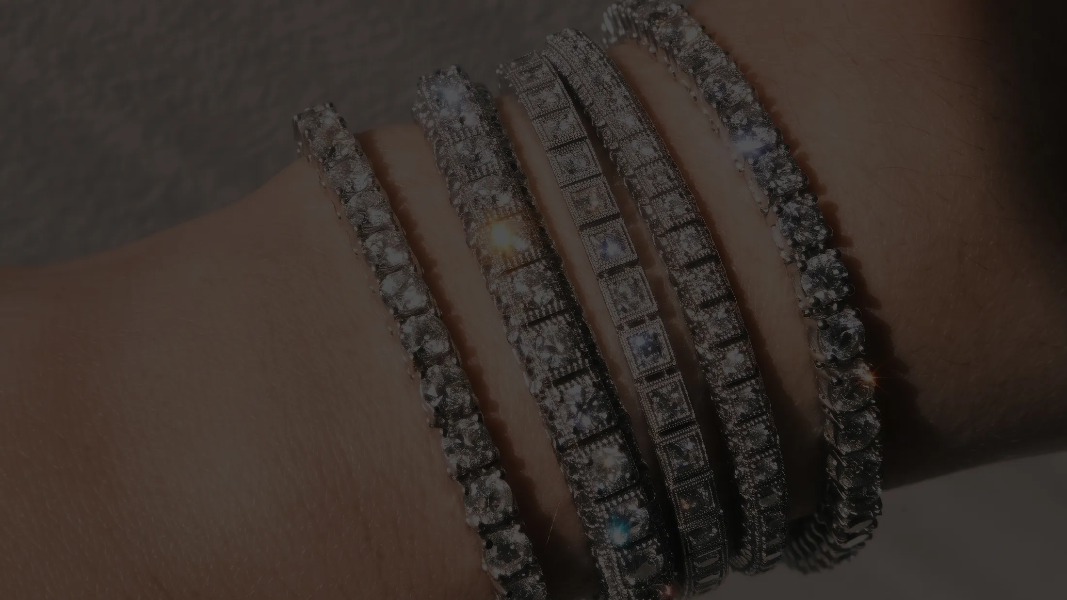 Five diamond bracelets with various designs on a wrist.