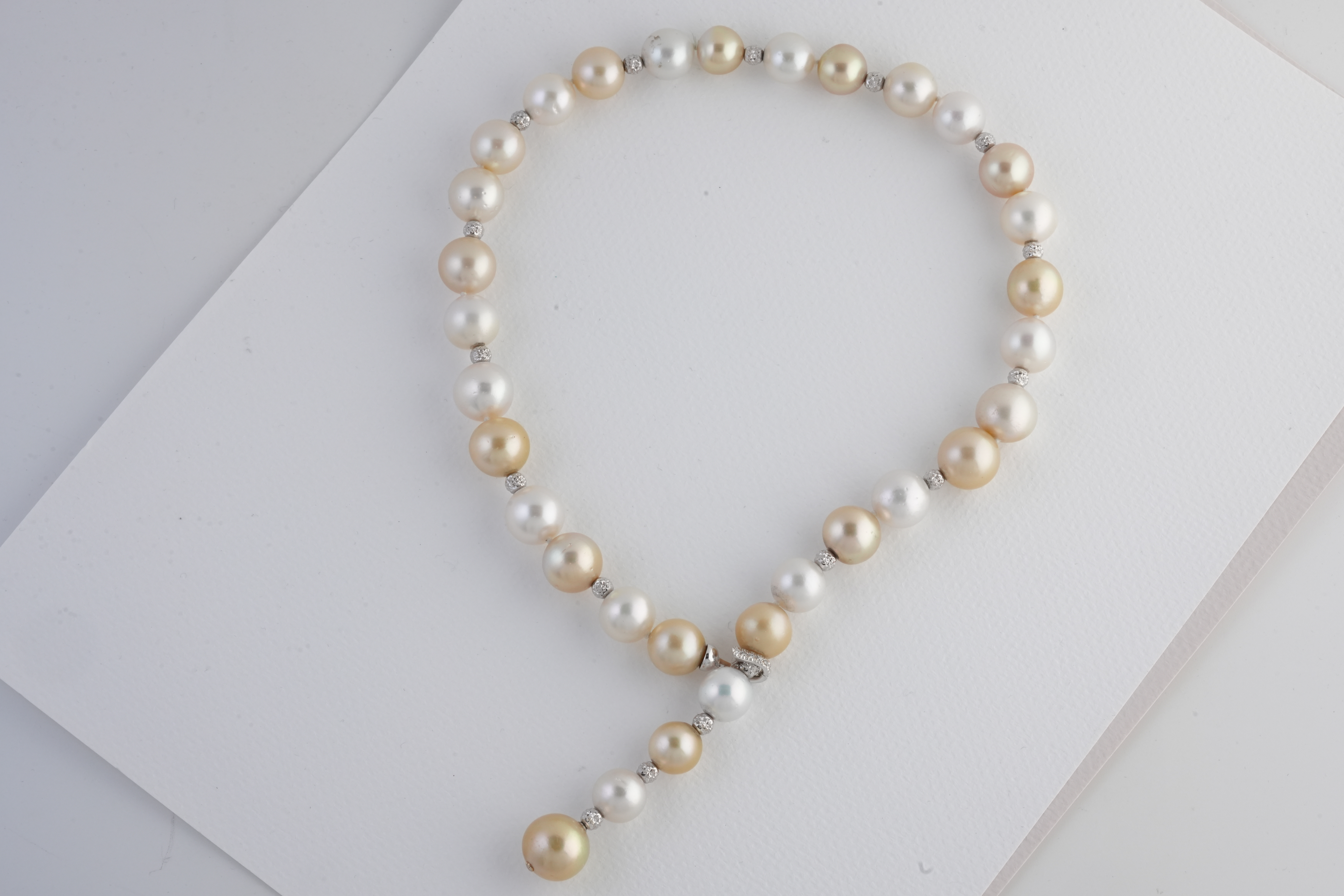 Hands knotting a strand of pearls onto silk thread