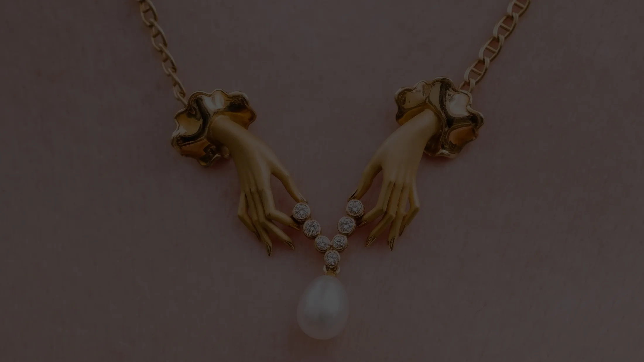 Gold necklace with hands holding diamonds and a pearl pendant.