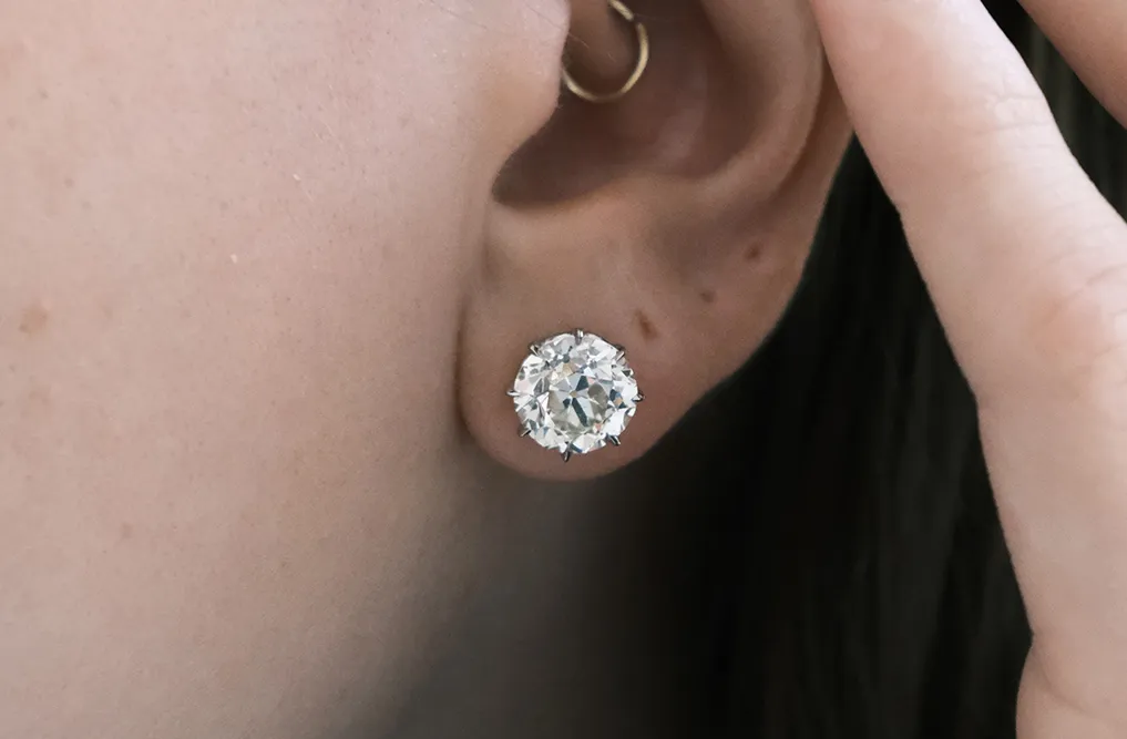 Close-up of an ear wearing a large round diamond stud earring.