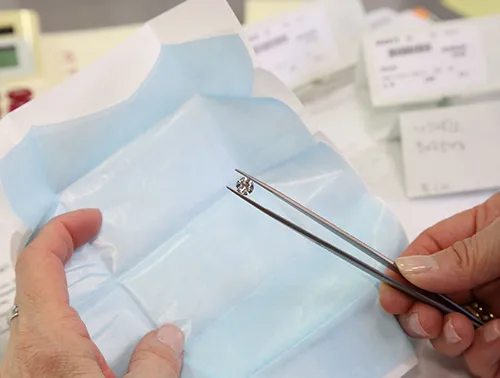 Diamond Held in Tweezers Above Paper 