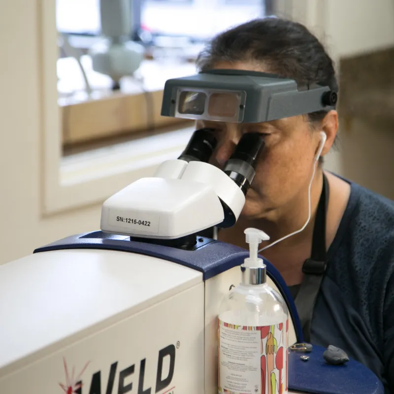 Jewelry lab technician inspecting jewelry through a microscope