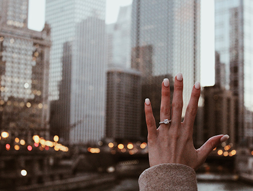 Woman holding up hand with engagement ring on.