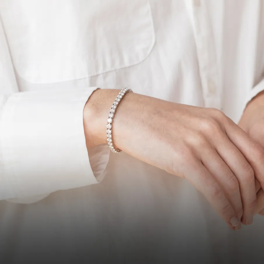 Elegant tennis bracelet worn on wrist, white shirt background. Click to shop now.